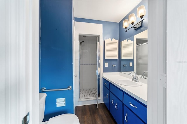 bathroom with vanity, toilet, hardwood / wood-style flooring, and a shower with door