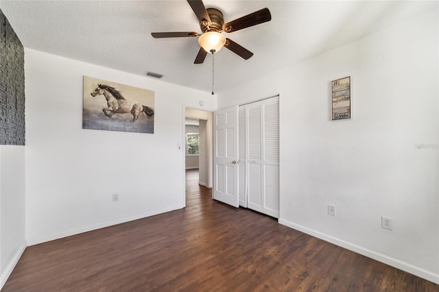 unfurnished bedroom featuring dark wood-type flooring, a textured ceiling, a closet, and ceiling fan