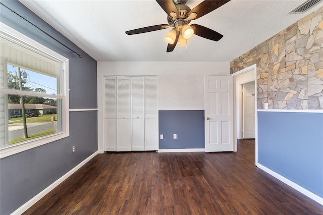 unfurnished bedroom with dark hardwood / wood-style flooring, a textured ceiling, a closet, and ceiling fan