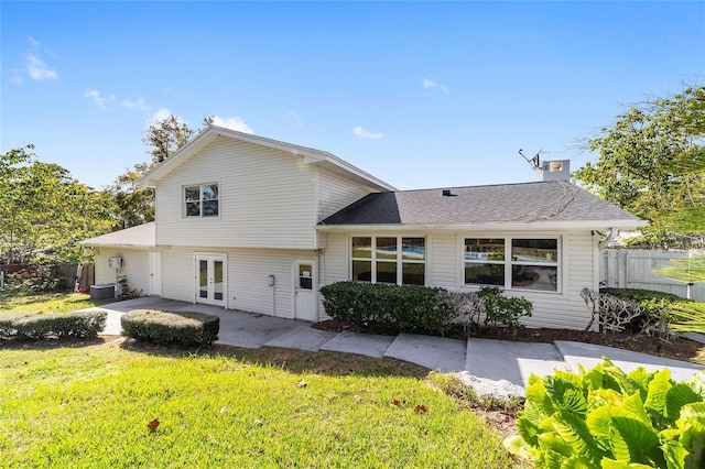 rear view of house with central air condition unit, french doors, a patio area, and a lawn