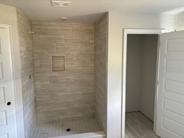 bathroom featuring wood-type flooring and tiled shower