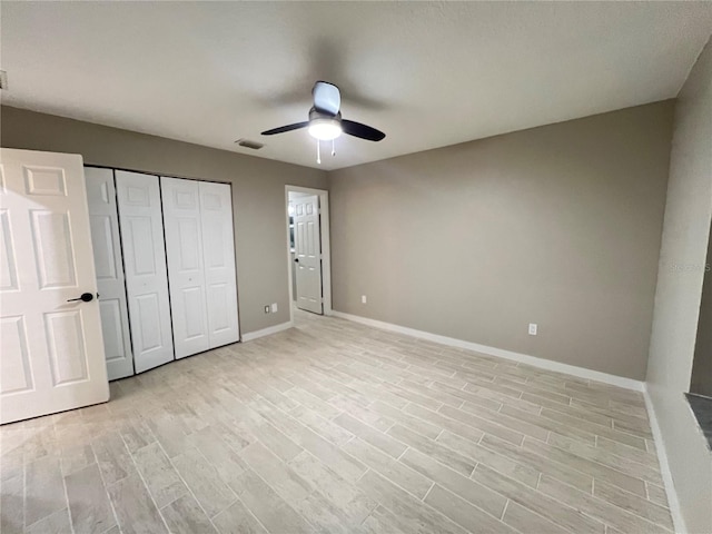 unfurnished bedroom with light wood-type flooring, ceiling fan, and a closet