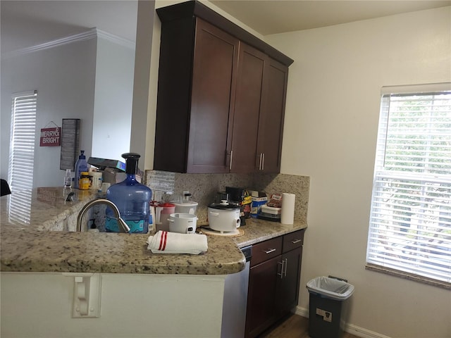 kitchen featuring dark brown cabinetry, light stone counters, kitchen peninsula, decorative backsplash, and ornamental molding