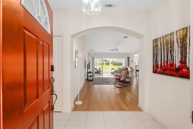 foyer featuring ceiling fan with notable chandelier and light hardwood / wood-style flooring