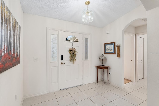 tiled entryway featuring a textured ceiling and a chandelier