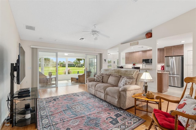 living room featuring light hardwood / wood-style flooring, ceiling fan, and vaulted ceiling