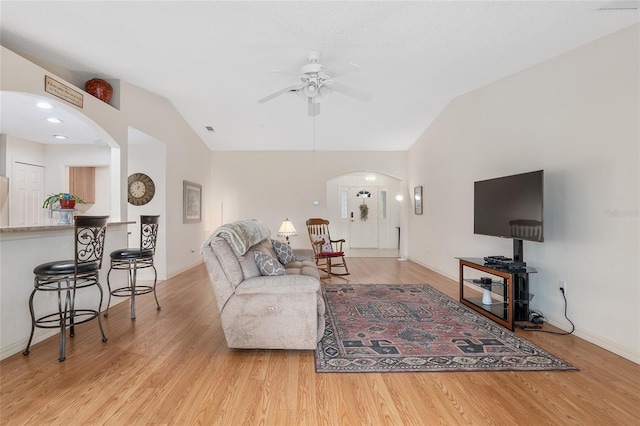 living room with light hardwood / wood-style flooring, lofted ceiling, and ceiling fan