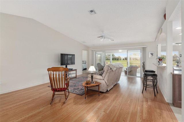 living room featuring ceiling fan, light wood-type flooring, and vaulted ceiling