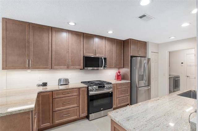 15596 SW 13th Cir, Ocala, FL 34473 - kitchen with appliances with stainless steel finishes, washer and clothes dryer, light stone counters, tasteful backsplash, and recessed lighting