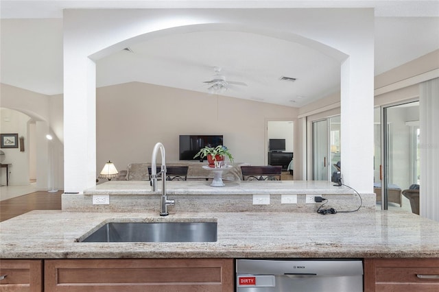 kitchen with vaulted ceiling, dishwasher, hardwood / wood-style floors, sink, and light stone countertops