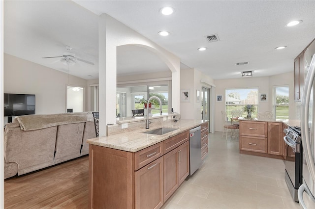 kitchen with light stone countertops, a wealth of natural light, sink, and stainless steel appliances