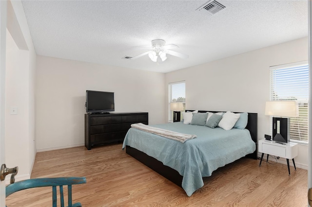 bedroom featuring a textured ceiling, ceiling fan, and light hardwood / wood-style flooring