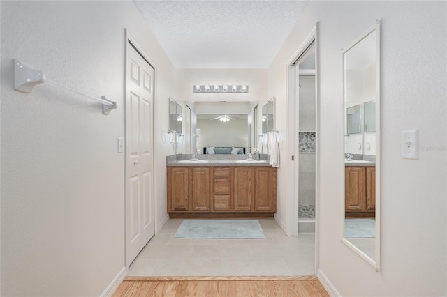 bathroom featuring a textured ceiling, hardwood / wood-style flooring, vanity, ceiling fan, and a shower