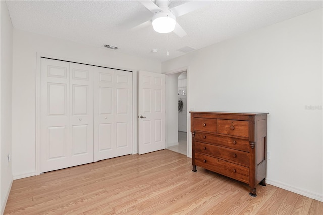 bedroom with a closet, light wood-type flooring, a textured ceiling, and ceiling fan