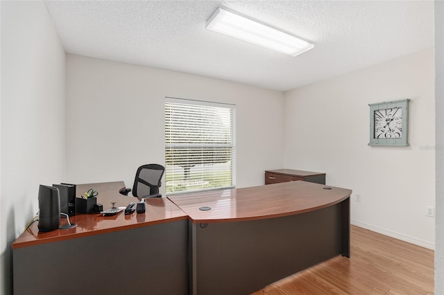 home office featuring a textured ceiling and light hardwood / wood-style flooring