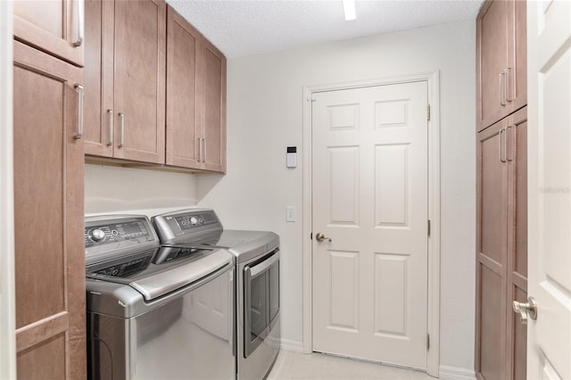 laundry area featuring washer and clothes dryer, cabinets, a textured ceiling, and light tile patterned floors