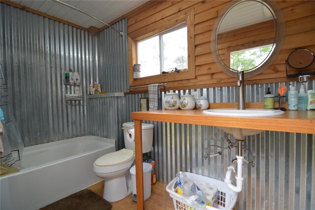 full bathroom with sink, shower / tub combo with curtain, wood-type flooring, wooden walls, and toilet