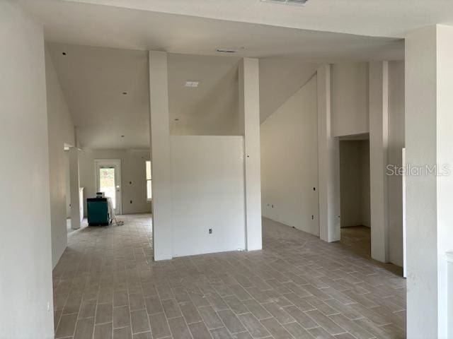 empty room with high vaulted ceiling and light hardwood / wood-style floors