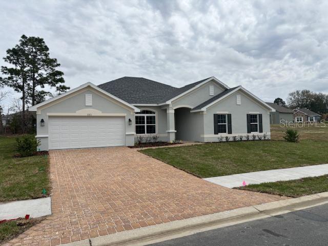 ranch-style house featuring a garage and a front lawn