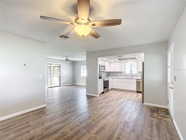 unfurnished living room featuring plenty of natural light, light hardwood / wood-style floors, a textured ceiling, and sink