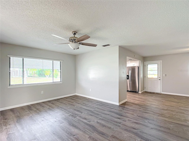 empty room featuring a textured ceiling, a wealth of natural light, and dark hardwood / wood-style floors