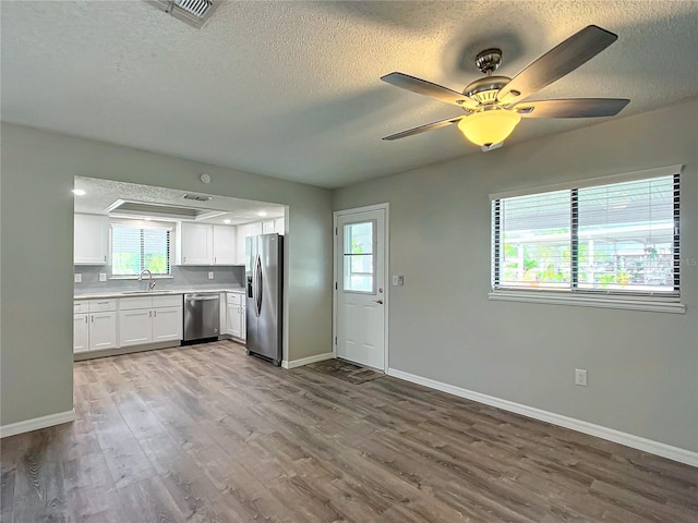 kitchen with plenty of natural light, white cabinetry, stainless steel appliances, and light hardwood / wood-style flooring