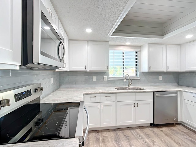 kitchen with appliances with stainless steel finishes, white cabinetry, and sink