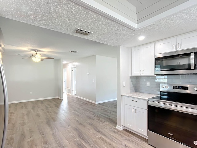 kitchen featuring a textured ceiling, stainless steel appliances, white cabinetry, and light hardwood / wood-style flooring