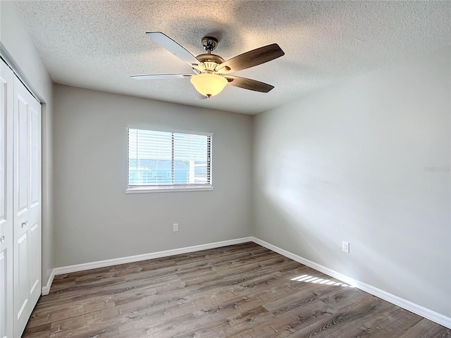 unfurnished bedroom with ceiling fan, a closet, a textured ceiling, and hardwood / wood-style flooring