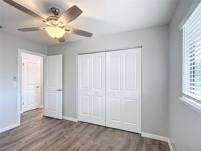 unfurnished bedroom featuring a closet, light hardwood / wood-style floors, and ceiling fan