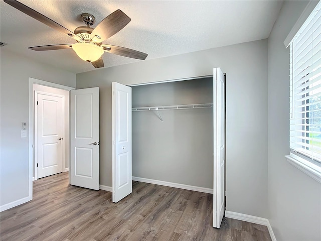 unfurnished bedroom with a closet, ceiling fan, light hardwood / wood-style flooring, and a textured ceiling