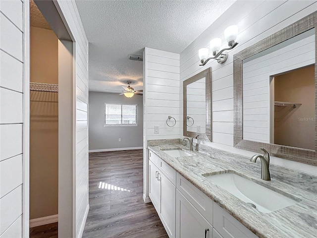 bathroom with vanity, a textured ceiling, ceiling fan, hardwood / wood-style flooring, and wood walls