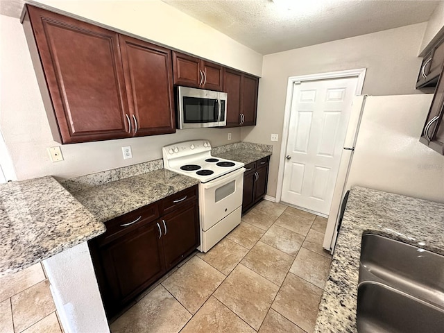 kitchen featuring light tile patterned flooring, white appliances, light stone countertops, and a textured ceiling