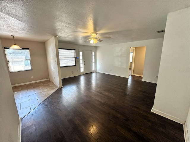 unfurnished living room featuring a textured ceiling, dark wood-type flooring, and ceiling fan