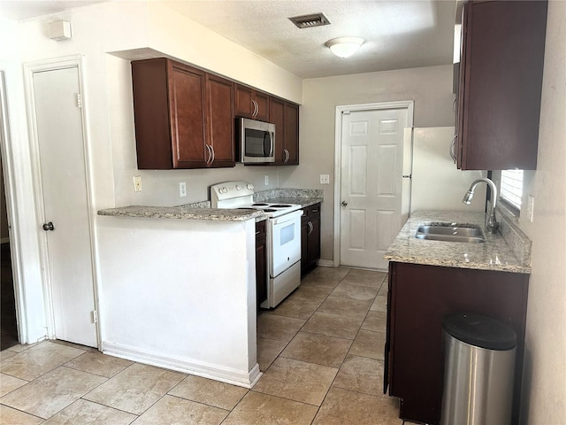 kitchen featuring sink, white appliances, light stone countertops, and a textured ceiling