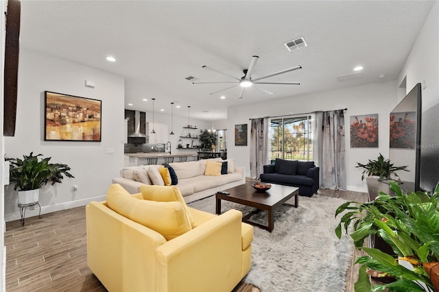 living room with light hardwood / wood-style floors, ceiling fan, and sink