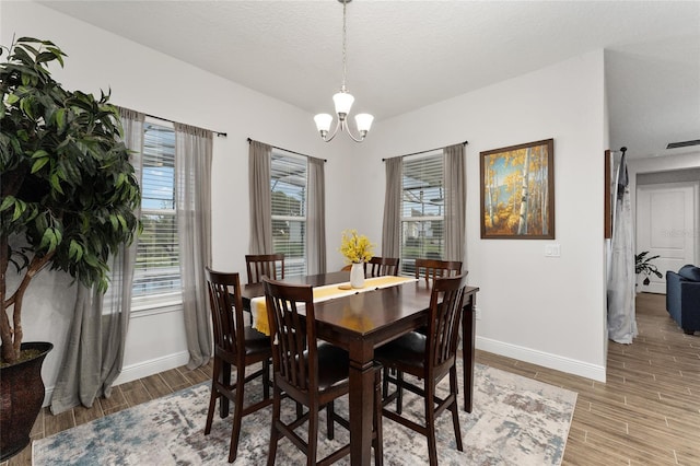 dining room with wood-type flooring, a textured ceiling, and a chandelier