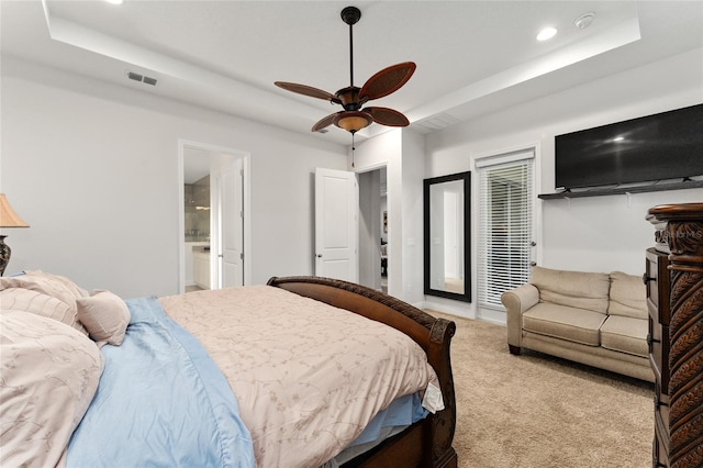 carpeted bedroom with ceiling fan, a tray ceiling, and connected bathroom