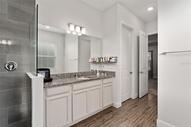 bathroom with tiled shower and vanity