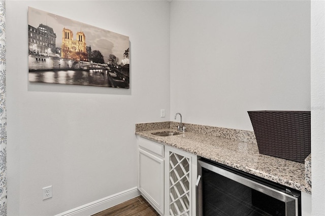 bar with dark wood-type flooring, sink, light stone countertops, white cabinetry, and wine cooler