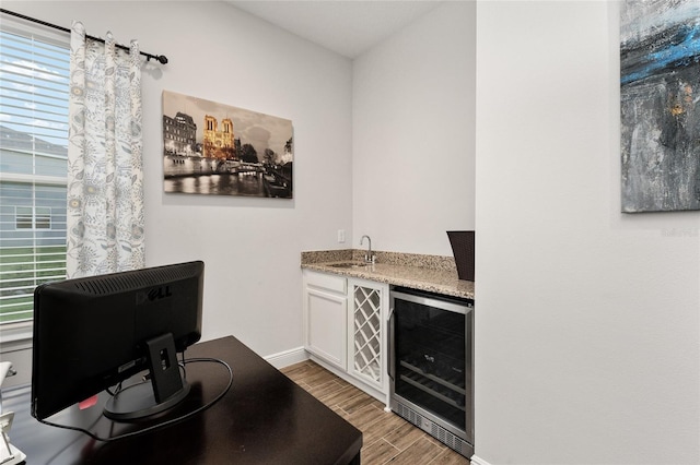 bar featuring white cabinetry, light stone countertops, sink, beverage cooler, and light hardwood / wood-style flooring