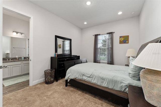 bedroom with light hardwood / wood-style floors, connected bathroom, and a textured ceiling