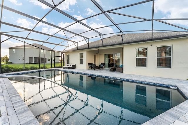 view of pool featuring glass enclosure, a lawn, and a patio