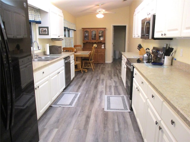 kitchen featuring vaulted ceiling, white cabinets, hardwood / wood-style flooring, sink, and appliances with stainless steel finishes