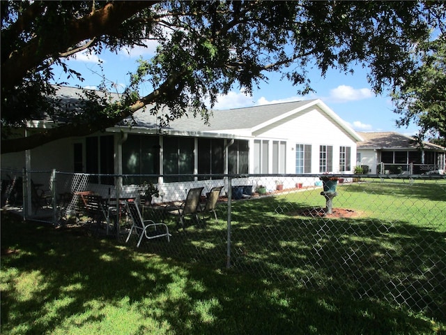 back of house featuring a lawn and a sunroom