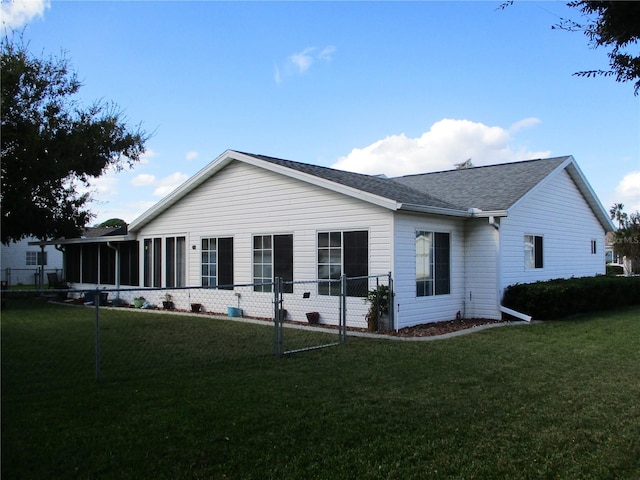 back of property with a sunroom and a yard