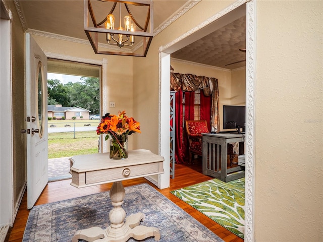 entryway featuring an inviting chandelier, ornamental molding, and wood-type flooring