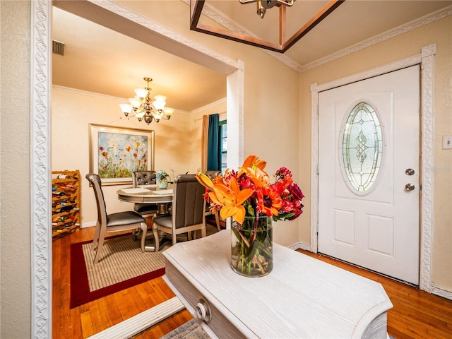 entryway featuring crown molding, a notable chandelier, and hardwood / wood-style floors