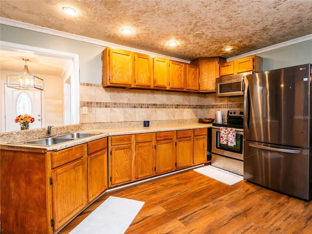 kitchen featuring tasteful backsplash, appliances with stainless steel finishes, ornamental molding, light hardwood / wood-style floors, and sink