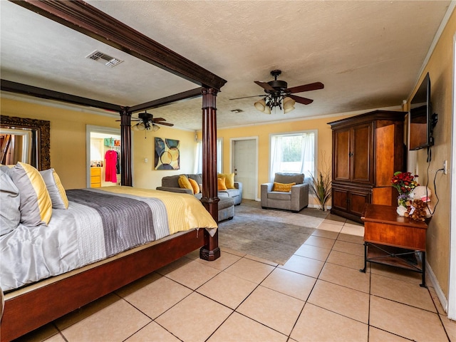 tiled bedroom featuring ornate columns, ceiling fan, and a textured ceiling